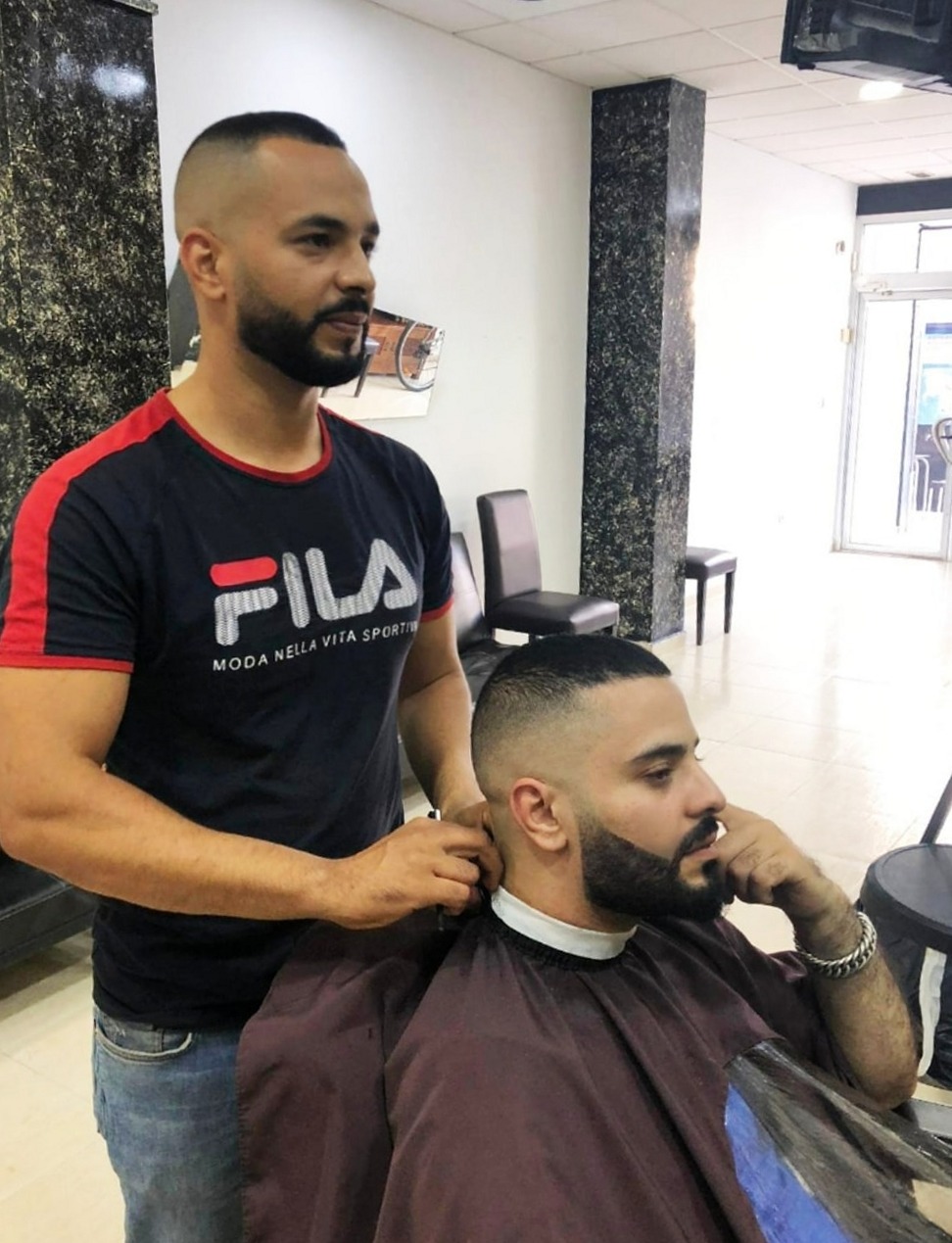 De barbier werkt de nek bij van een klant met baard